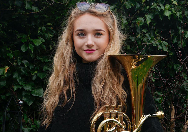 College age woman poses with her baritone euphonium Stock Photo